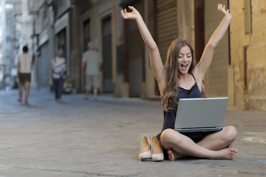 mulher sentada com notebook e as mãos para cima mostrando liberdade